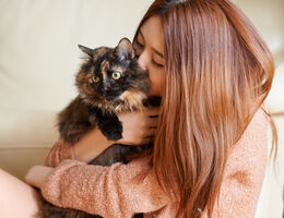 A woman hugs a cat.